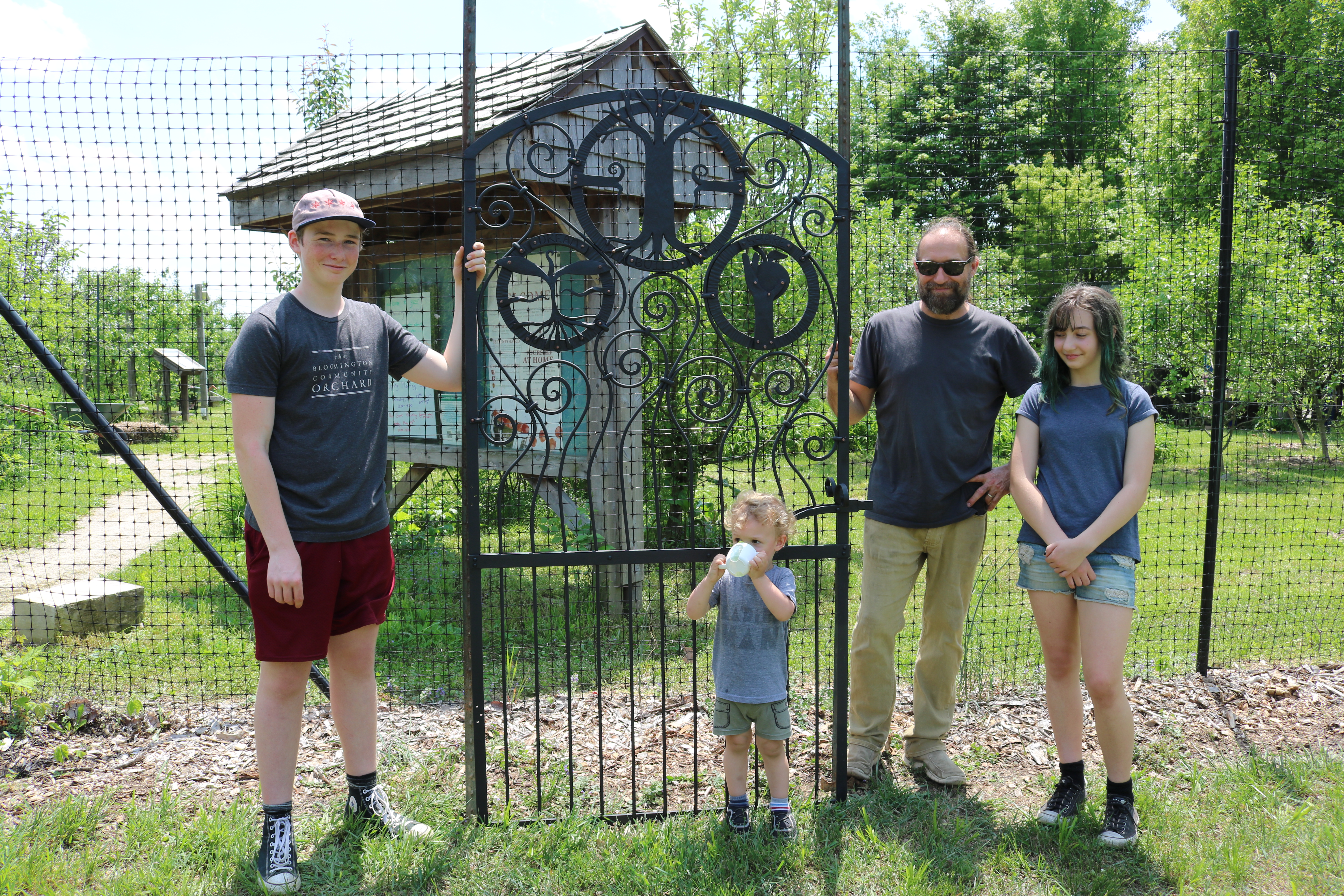 Paolo Ansaldo, Jason Nickel, and Iris Nickel stand next to the orchard gate door